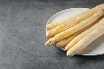 Raw white asparagus spears on grey textured table, closeup. Space for text