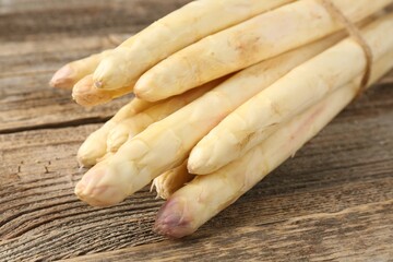 Raw white asparagus spears on wooden table, closeup