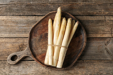Bunch of raw white asparagus spears on wooden table, top view