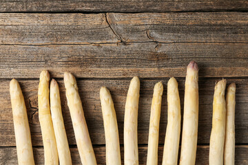 Raw white asparagus spears on wooden table, flat lay. Space for text