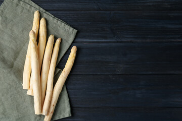 Raw white asparagus spears on black wooden table, flat lay. Space for text