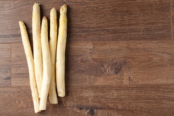 Raw white asparagus spears on wooden table, flat lay. Space for text