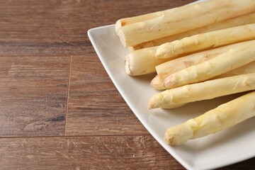 Raw white asparagus spears on wooden table, closeup. Space for text