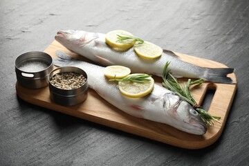 Fresh raw seabass with spices on black table. Fish and seafood delicacies
