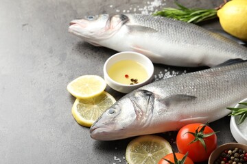 Fresh raw seabass with spices on grey table, closeup. Fish and seafood delicacies