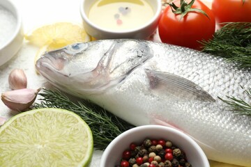 Fresh raw seabass with spices on white table, closeup. Fish and seafood delicacies