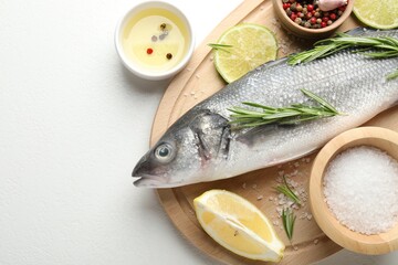 Fresh raw seabass fish with spices on white table, top view and space for text. Seafood delicacies