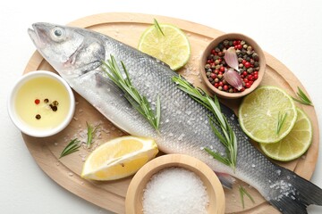 Fresh raw seabass with spices on white table, top view. Fish and seafood delicacies