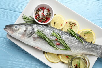 Fresh raw seabass with spices on blue wooden table, top view. Fish and seafood delicacies