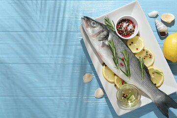 Fresh raw seabass fish with spices on blue wooden table, flat lay and space for text. Seafood...