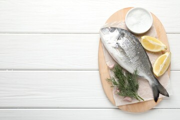 Fresh raw dourade fish with spices on white wooden table, top view and space for text. Seafood delicacies