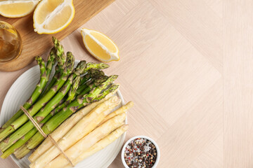 Different raw asparagus spears and spices on wooden table, flat lay. Space for text