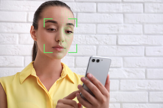 Woman unlocking her smartphone with facial recognition app indoors. Biometric verification