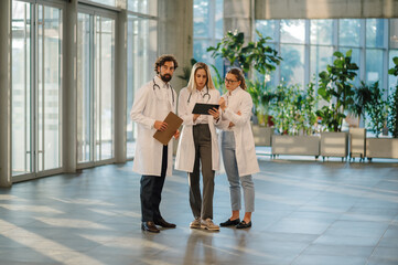 Doctors using tablet and discussing patient's medical history in hospital lobby
