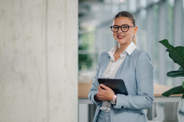 Smiling businesswoman holding tablet in modern office setting