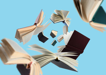 Hardcover books flying against light blue background