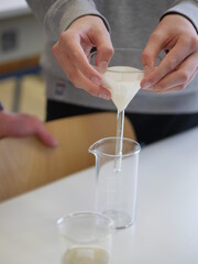 Person is pouring a liquid into a glass beaker