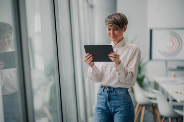 Businesswoman using digital tablet in modern office by window