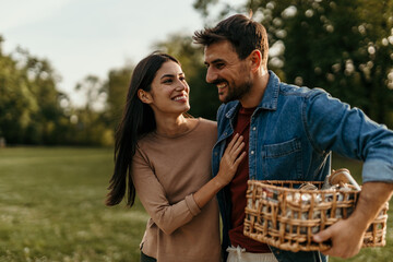 Couple walking in park, carrying picnic basket, enjoying romantic day outdoors