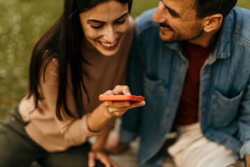 Happy couple using smartphone outdoors, sharing a special moment