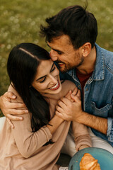 Happy couple embracing and smiling during romantic picnic in park