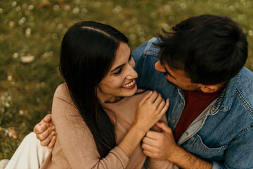 Happy couple enjoying romantic moments in meadow, embracing and smiling