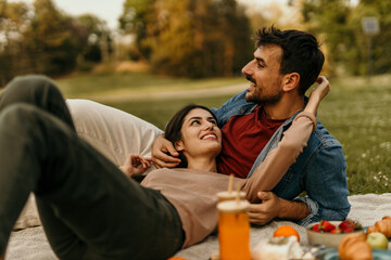 Happy couple enjoying romantic picnic in park during golden hour
