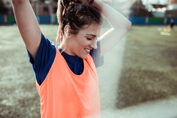 Female soccer player smiling and stretching during practice on field