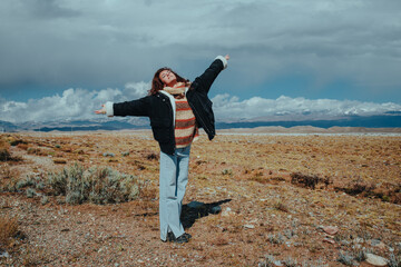 Young happy woman posing on mountains background in Kyrgyzstan