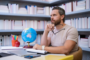 Portrait of teacher in library classroom. Handsome teacher in university library. Teachers Day....