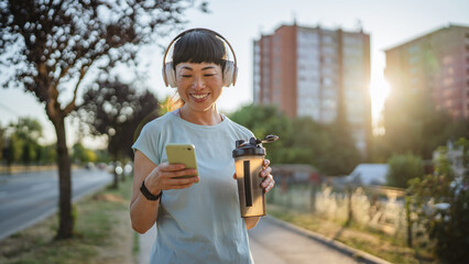 japanese woman drink protein shake and use mobile phone after jogging