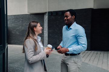 Business colleagues chatting outside office building during coffee break