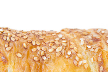 Close-up of golden brown puff pastry topped with toasted sesame seeds on white background. Ideal for bakery, breakfast, and food-related concepts.