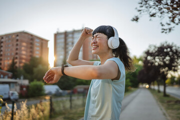 Happy japanese woman runner with headphones checking smart watch