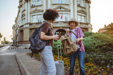 two beautiful women friends with suitcases discuss on the street