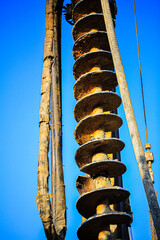 Vertical view of a large industrial auger drill used in construction and earth drilling. The image...