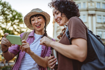 two women tourist use map on mobile phone to find destination location