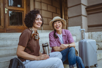 two women tourist friends with suitcases discuss on staircase