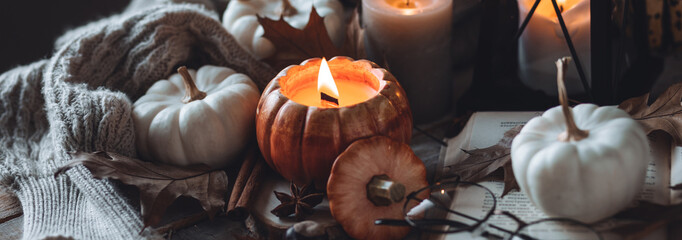 Cozy autumn home still life scene. Ceramic handmade pumpkin mug with burning candle near the...