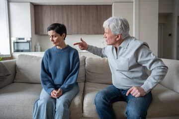 Angry senior man shouting and blaming wife, senior couple facing domestic issues at home....