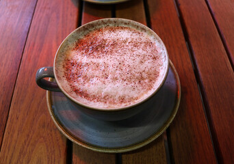 Cappuccino with cocoa powder in a cup on a wooden table