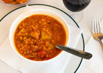 Stewed lentils with suasage and vegetables with thick tomato sauce. Typical Spanish cuisine