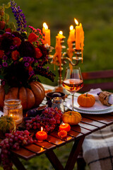 Fall table decoration with pumpkins, wine, candles. Family cozy thanksgiving dinner arrangement outdoors, wedding elegant decor. Countryside style, simple handmade setting, autumn mood, inspiration