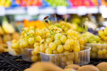 Bunches of kish-mish grapes, lined in boxes for sale in a store on the counter