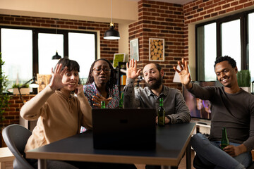 Male and female individuals waving towards device screen, participating in virtual call with long...