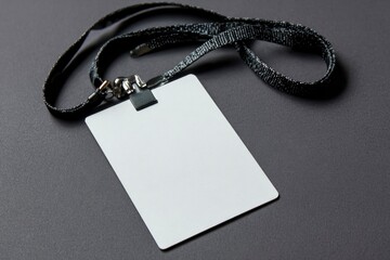 A closeup shows a blank white identification card attached to a patterned black lanyard resting on a gray surface
