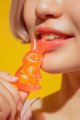 A close-up of an Asian woman eating a figure of an gelatin rabbit 1
