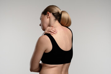 Naklejka premium Woman Experiencing Shoulder Pain with Visible Back View