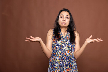 Confused indian lady with pursed lips and shrugged shoulders, expressing uncertainty and ignorance....