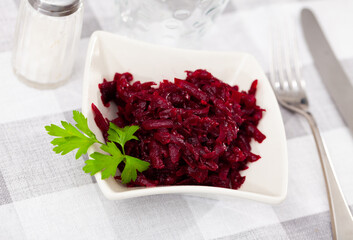 Traditional salad of Russian cuisine from boiled grated beetroot, decorated with a sprig of parsley